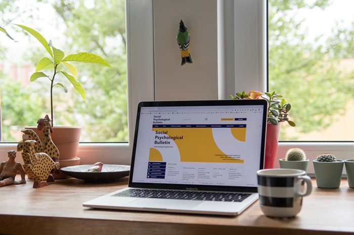 Laptop on desk in front of plants next to coffee cup