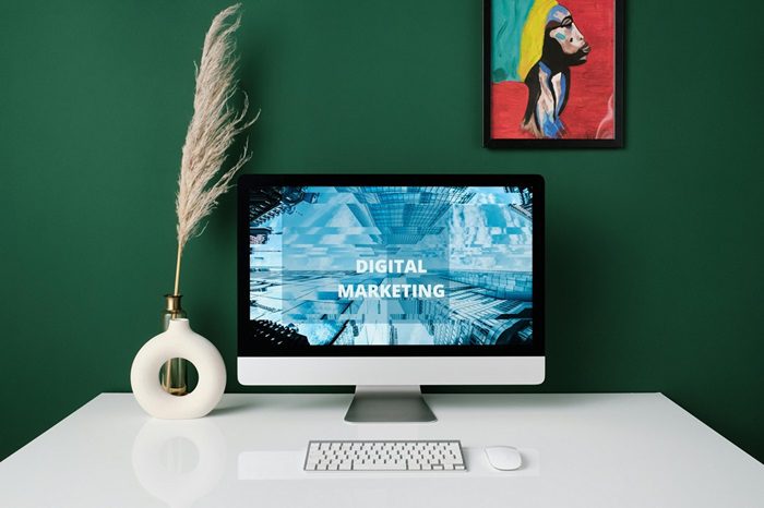 Green wall with African painting behind desk with laptop